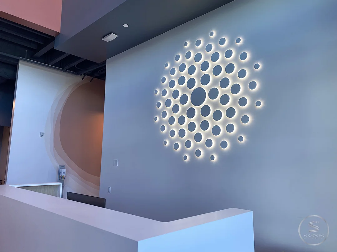 Circular halo-lit Allogene logo mounted above a reception desk