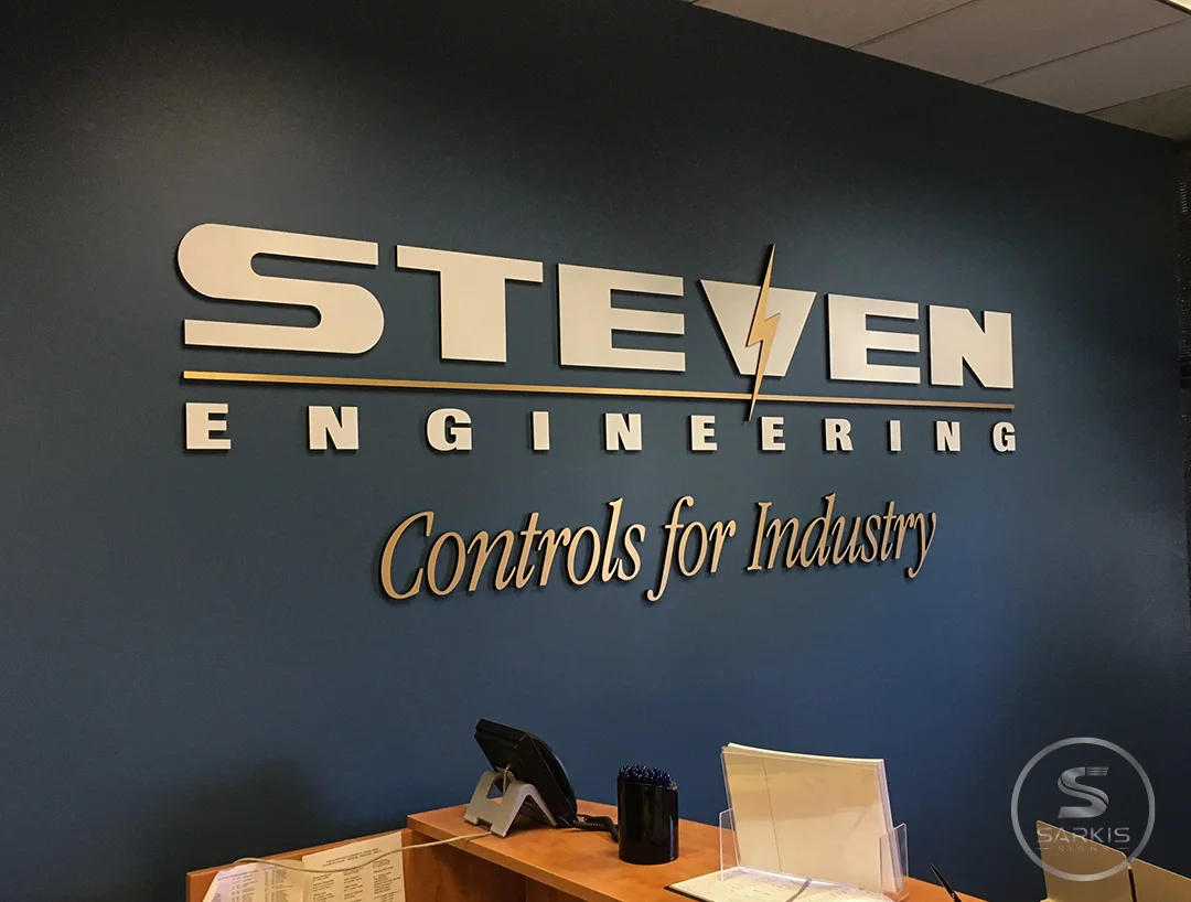 Metallic Steven Engineering dimensional lettering on a dark reception wall